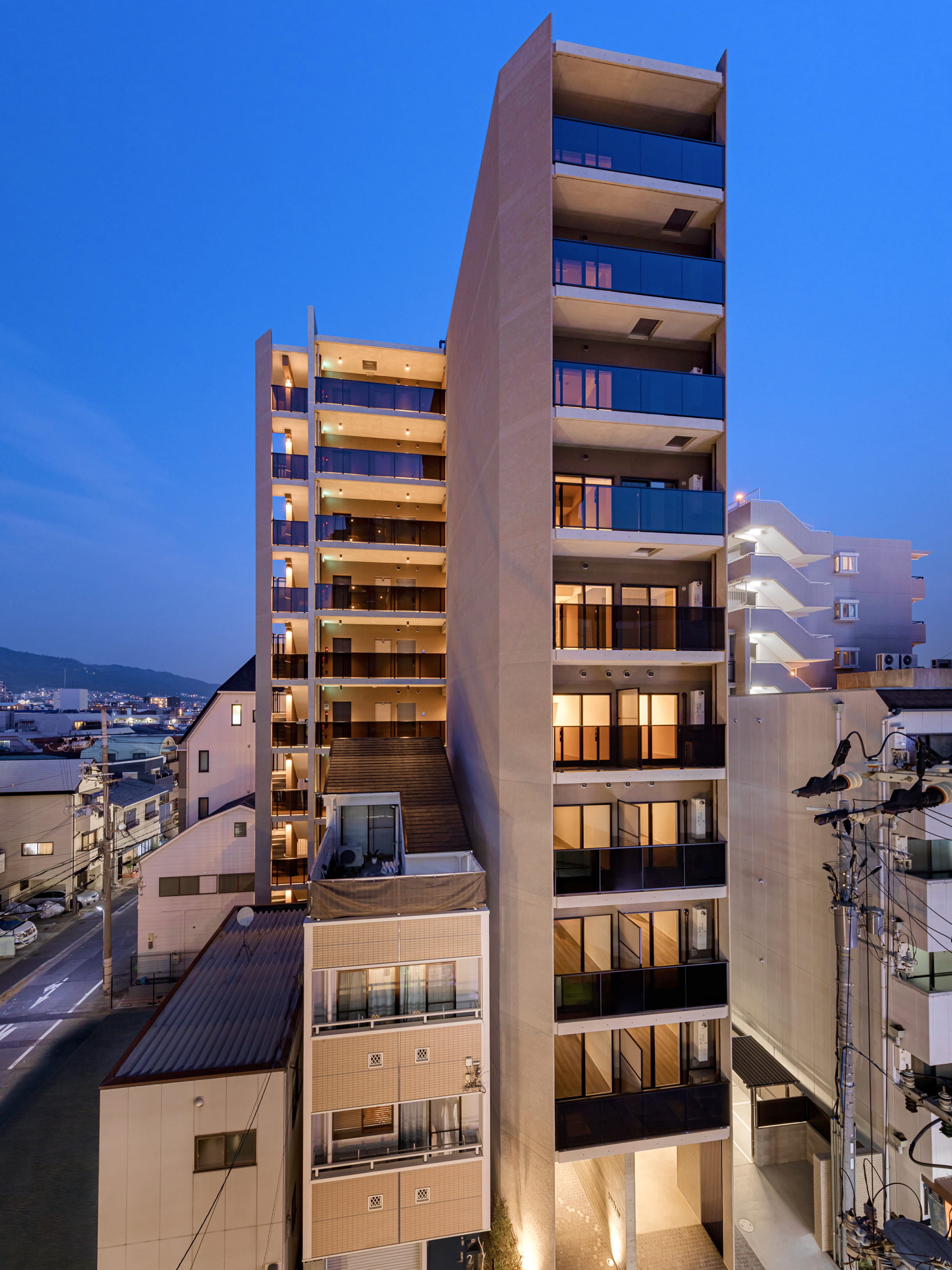 夜景の中に建つ、ガラス手すりとコンクリート外壁が特徴のスタイリッシュな高層マンション