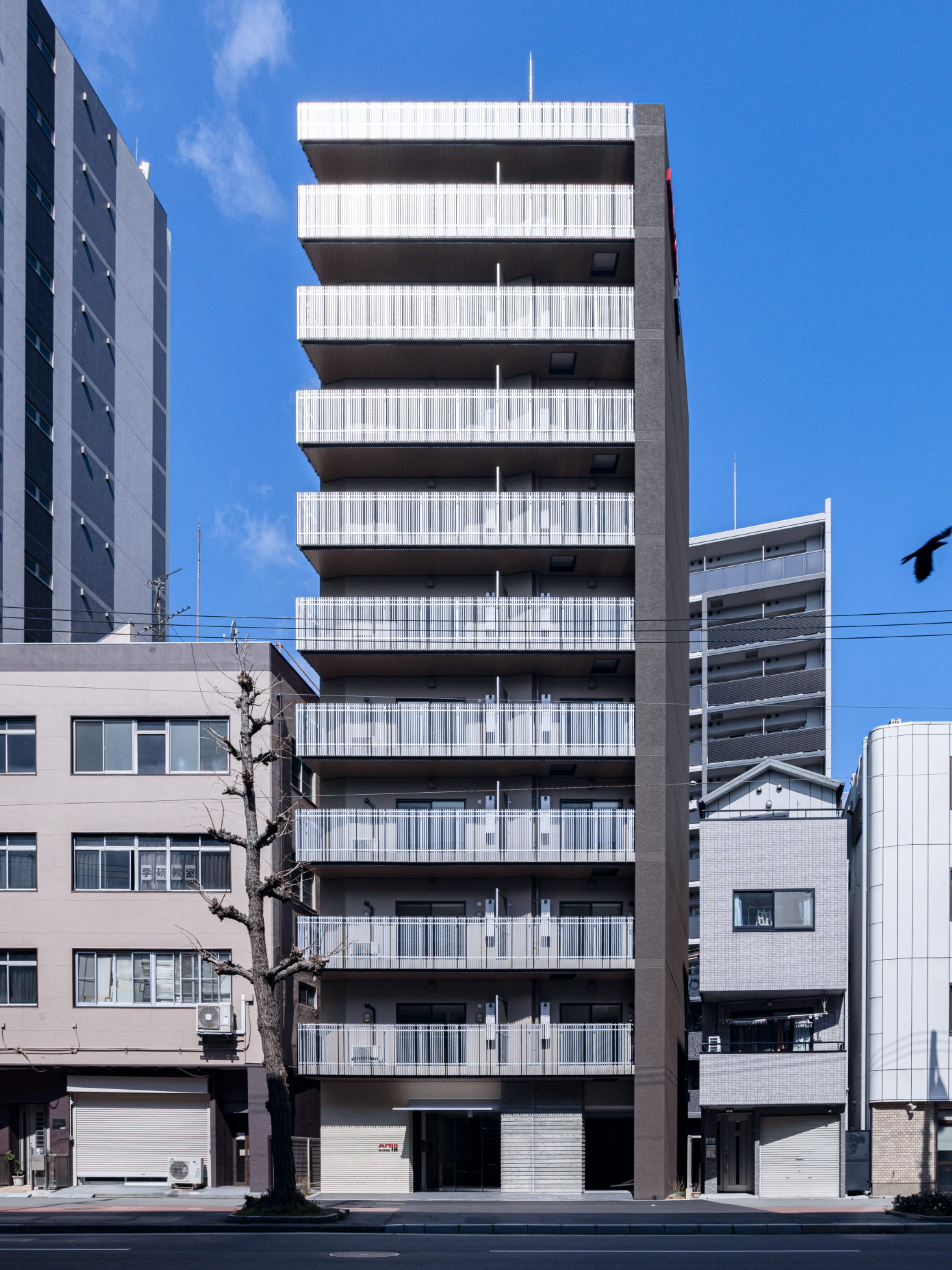 青空の下、縦格子の手すりと木目調の軒天井が印象的な現代的高層マンションのバルコニー