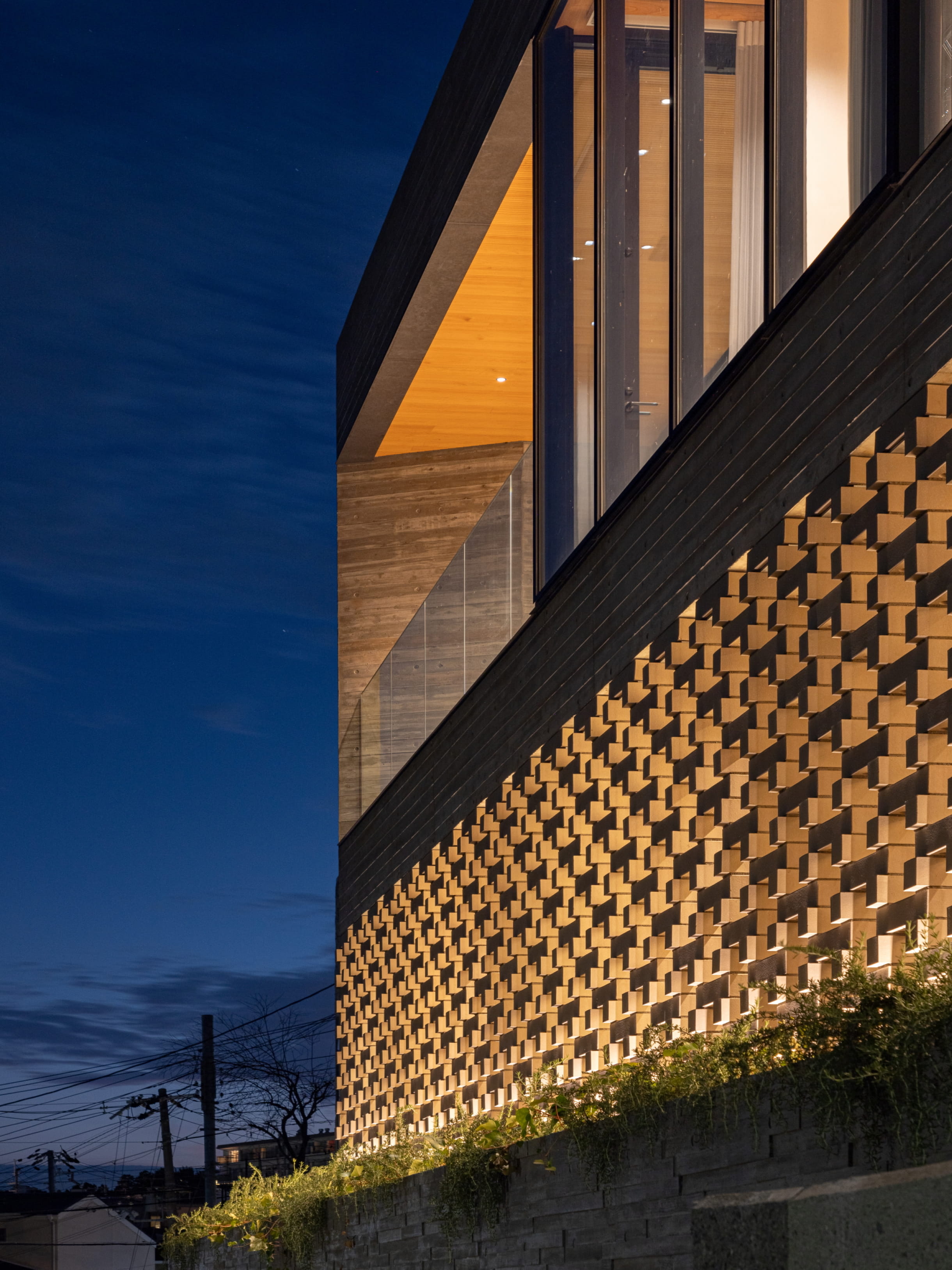 夜の空を背景に、立体的なレンガ模様の壁面がライトアップされたモダンな建築物