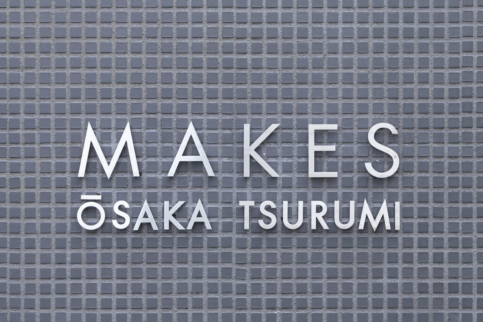 タイル張りの壁面に掲げられた、MAKES OSAKA TSURUMI の館銘板