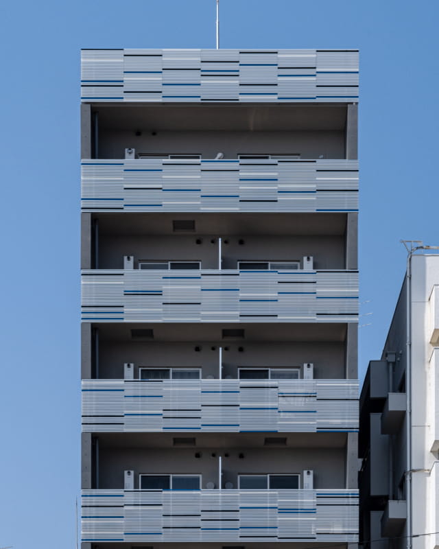 グレーを基調とした外壁と縦長のフォルムが特徴的な、都市型マンションの完成予想図