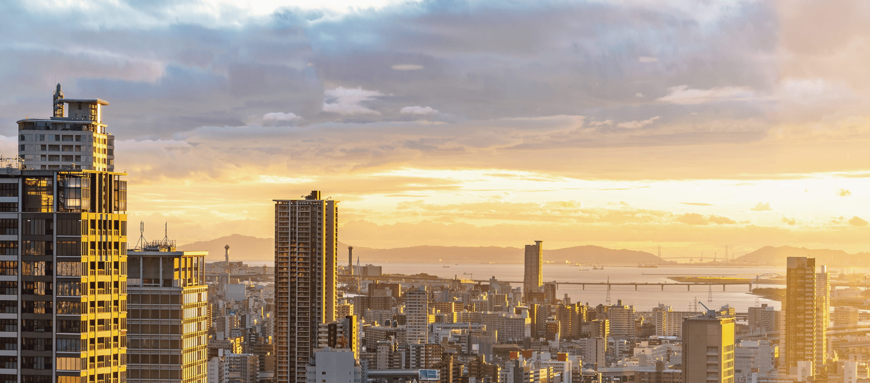 高層ビルが立ち並ぶ都市の街並みを、夕焼けが美しく照らしている風景